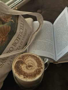 a cup of coffee sitting next to an open book