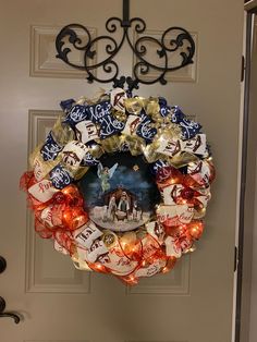 a wreath is hanging on the front door with some lights around it and an image of a nativity scene