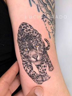 a woman's arm with a black and white tattoo of a leopard on it