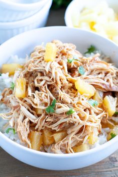 a white bowl filled with shredded chicken and pineapples