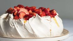 a cake with white frosting and strawberries on top is sitting on a plate