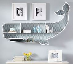 there is a whale shaped shelf on the wall in this room with pictures above it