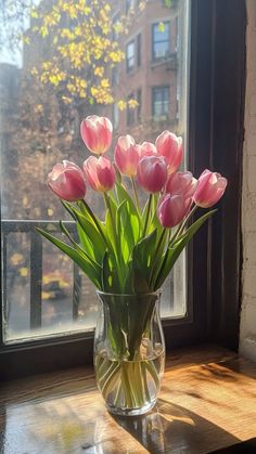 a vase filled with pink tulips sitting on top of a window sill