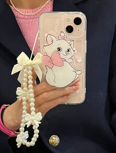 a woman holding a phone case with a cat on it and pearls around her wrist