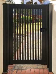 an iron gate with vertical bars on the top and bottom, leading to a driveway