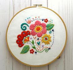 a white wall hanging with a colorful embroidered flower design on it's front and side