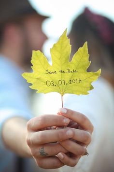 a person holding a yellow leaf with the words save the date written on it