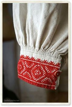 a red and white pillow hanging from the back of a chair with an embroidered design on it