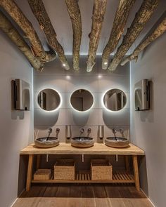 a bathroom with two sinks, mirrors and wooden beams in the ceiling is lit by lights