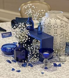 blue vases with baby's breath flowers and candles on a white table cloth