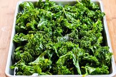 a white dish filled with green vegetables on top of a wooden table