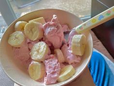 a bowl filled with ice cream and sliced banana's next to a plastic spoon