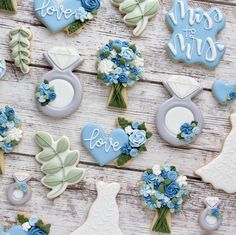 decorated cookies are arranged on a wooden table with blue flowers and bride's dress