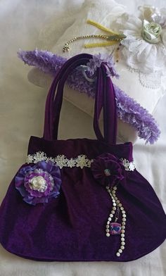 This elegant handheld bag is made out of velvety material suitable for any occasion whether it be your daughter's wedding or Christmas party.  It is nicely decorated with beautiful handmade flowers, a few white beads, chains and white lace on top. The inside of this beauty is lined with purple satin-like material. Purple Handmade Wedding Bags, Handmade Velvet Bags For Gifts, Velvet Rectangular Wedding Bags, Rectangular Velvet Wedding Bag, Rectangular Velvet Wedding Bags, Handmade Velvet Wedding Bag, Handmade Velvet Wedding Bags, Shabby Chic Boho, Recycle Bag