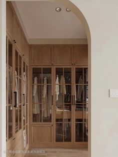 an open closet with lots of clothes on shelves and glass doors in the center, along with a wooden floor