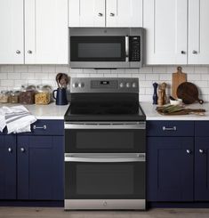 a kitchen with blue cabinets and white counter tops, stainless steel stove top oven and microwave