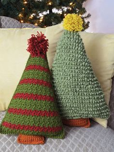 two crocheted christmas trees sitting next to each other on top of a bed