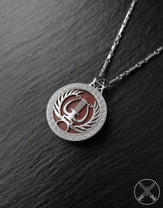 a silver and red necklace on a black surface with the letter g in it's center