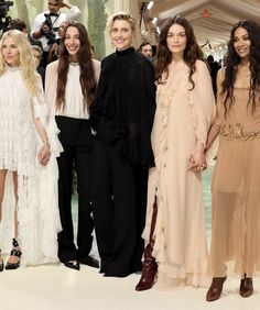 several women standing next to each other in front of a group of people at a fashion show