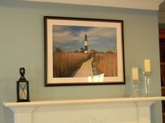 a white fireplace with a painting hanging above it and candles on the mantle next to it