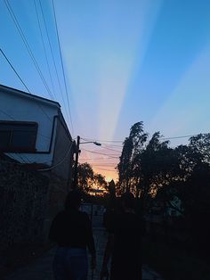 two people walking down the street at sunset