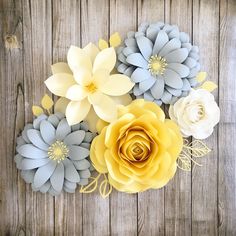 paper flowers are arranged on a wooden surface with yellow and gray petals in the center