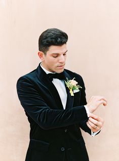 a man in a tuxedo adjusting his bow tie