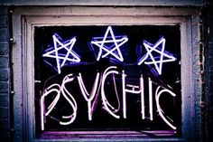 a neon sign that says psychic on the side of a building with stars above it