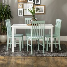 a dining room table with four chairs and a potted plant on the floor next to it