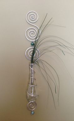 a glass vase with a plant in it on a table next to a white wall