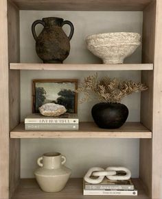 three shelves with vases, books and other items on top of them in a room