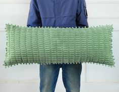 a person holding a green pillow in their hands