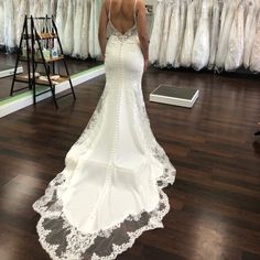 a woman in a white wedding dress looking at her gowns on the rack,