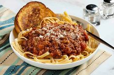 a white bowl filled with spaghetti and bread