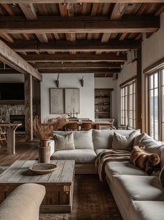 a living room filled with lots of furniture and wooden flooring next to large windows