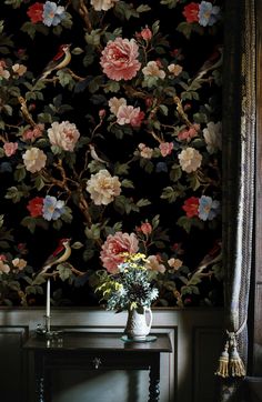 a vase with flowers sitting on top of a table next to a wallpapered wall