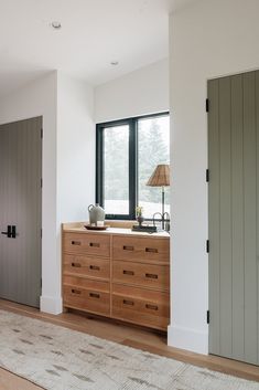 an empty room with a dresser and large window