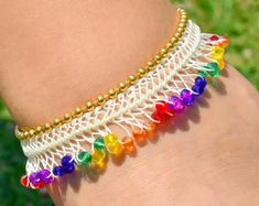 a close up of a person's arm wearing a bracelet with multicolored beads