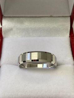 a silver ring in a box with white cloth on it's sides and red handles