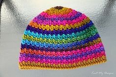 a multicolored crocheted hat hanging from a hook on a metal surface