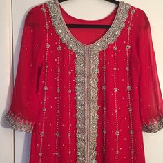 a red dress hanging on a white door with beads and sequins all over it