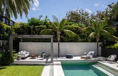 an outdoor swimming pool with lounge chairs and palm trees in the backround area