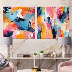 two paintings on the wall in a living room with pink chairs and a coffee table