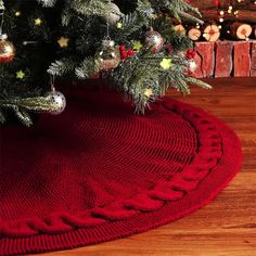 a christmas tree with ornaments on it and a red rug in front of the tree