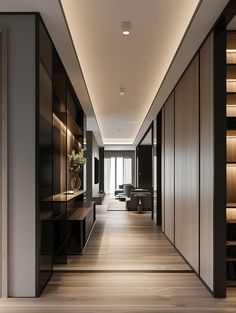 a long hallway with wooden flooring and black cabinets on both sides is lit by recessed lighting