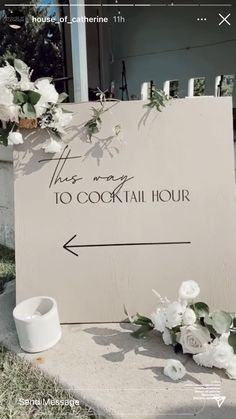 there is a sign that says this way to cocktail hour and flowers on the sidewalk