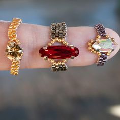 a person's hand with three rings on it and a red stone in the middle