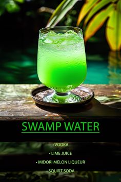 a green drink sitting on top of a wooden table next to a swimming pool with the words swamp water