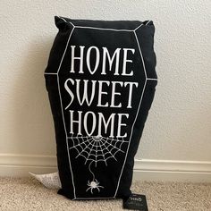 a black pillow with the words home sweet home printed on it and a spider web