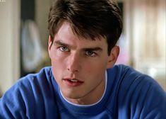 a close up of a person wearing a blue shirt and looking at the camera with a serious look on his face